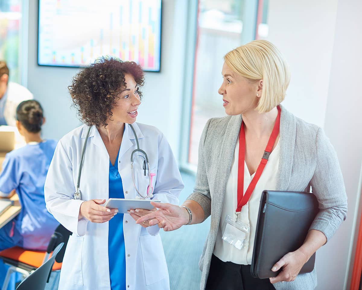 A doctor and healthcare admin talk after a meeting